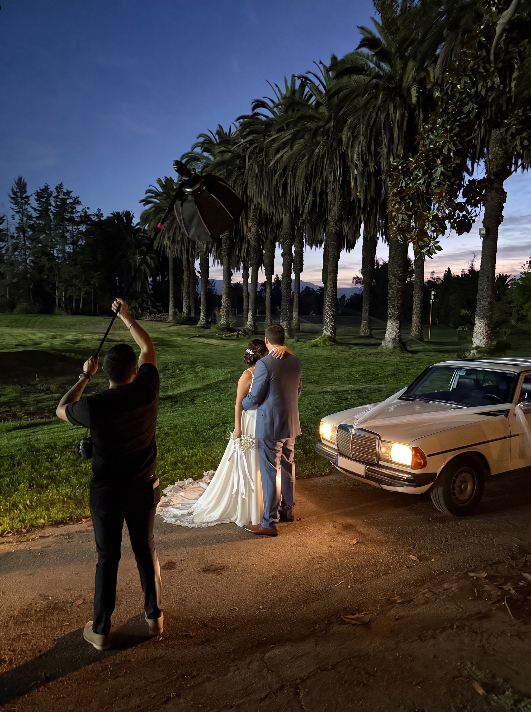 El Mercedes-Benz 230 E blanco esperando a los novios en una avenida de palmeras